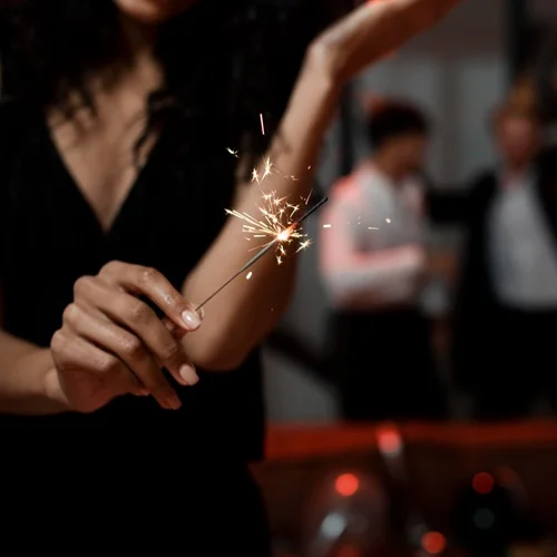 woman holding sparkler dressed in black uptown salon
